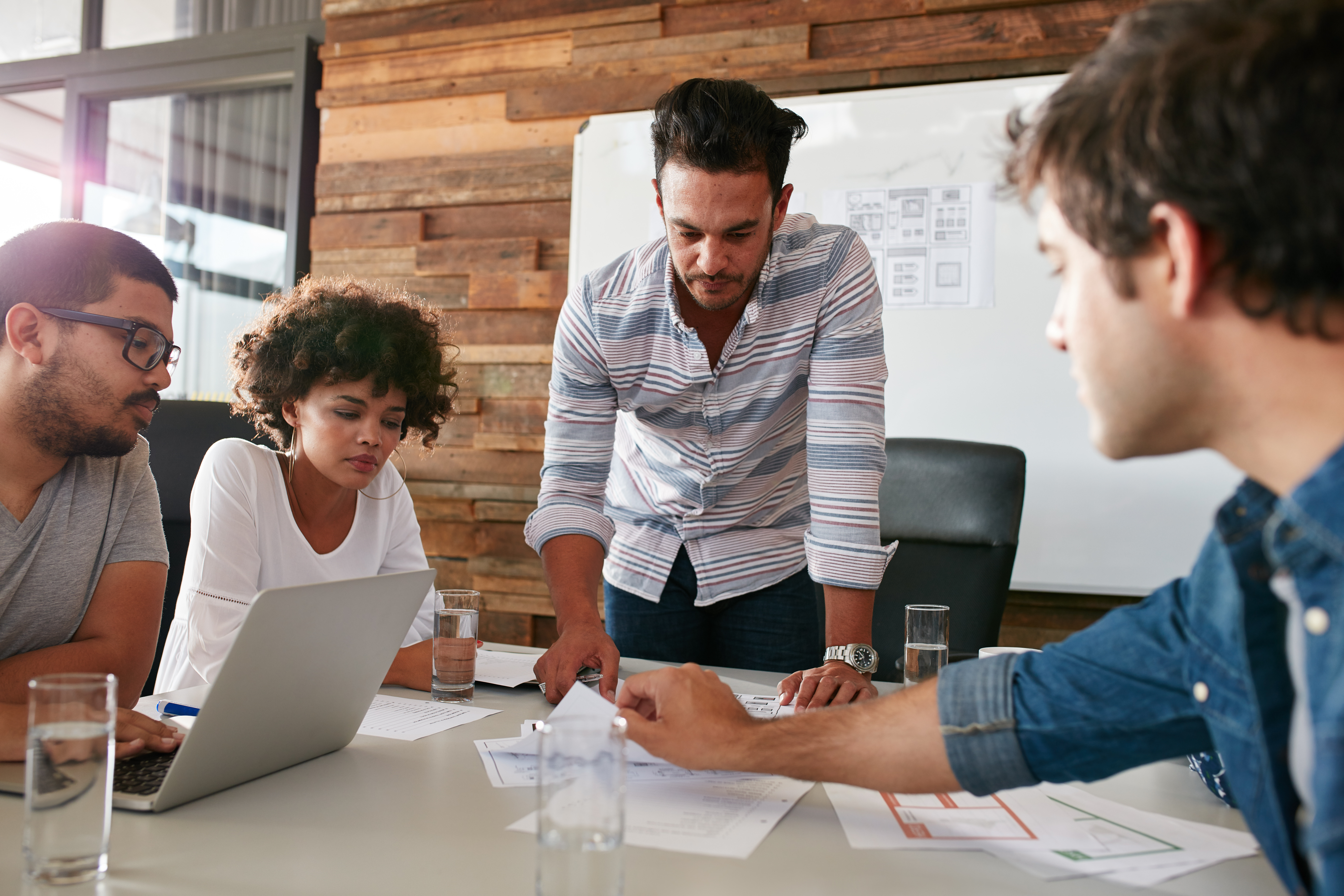 people meeting around a conference table with whiteboard behind them.